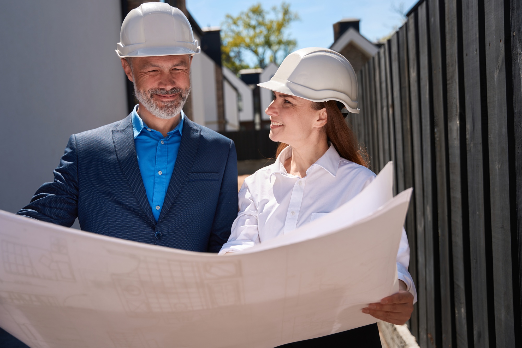 Male and female architects looking at blueprint and smiling